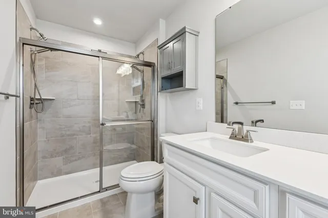a bathroom with a shower sink vanity mirror and toilet