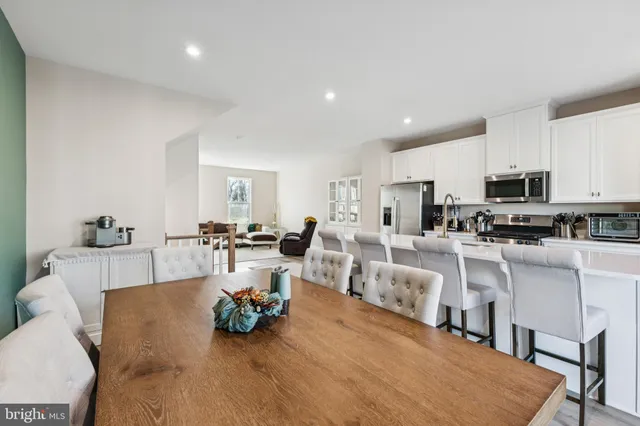 a living room with white furniture and a dining table with kitchen view