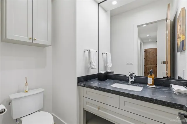 a bathroom with a granite countertop toilet sink and mirror