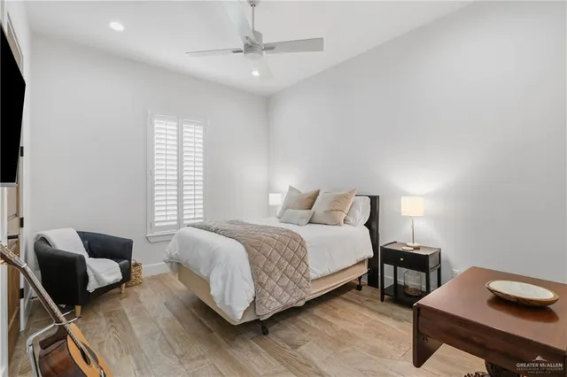 a bedroom with a bed a couch and a dresser with wooden floor