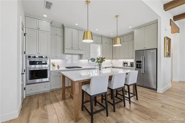 a kitchen with stainless steel appliances granite countertop a sink a stove a refrigerator and island with wooden floor