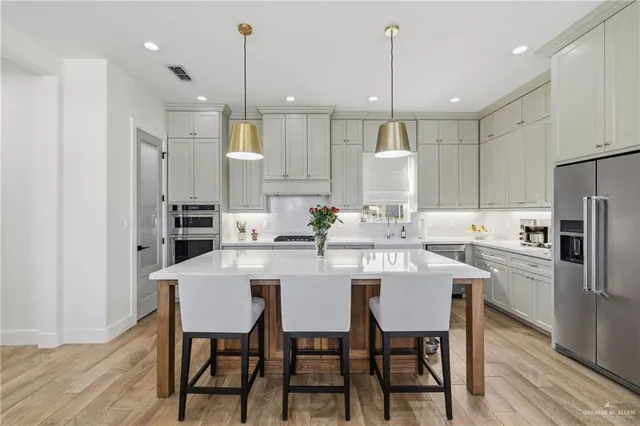 a kitchen with stainless steel appliances kitchen island granite countertop a dining table chairs and white cabinets
