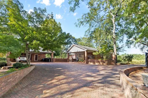 a view of a house with a yard and large trees