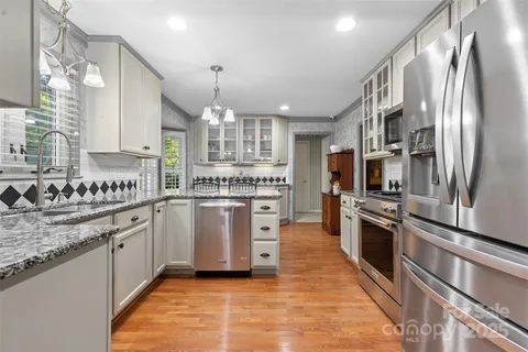 a kitchen with stainless steel appliances granite countertop a sink and a stove