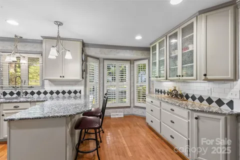 a kitchen with granite countertop a stove a sink and white cabinets with wooden floor