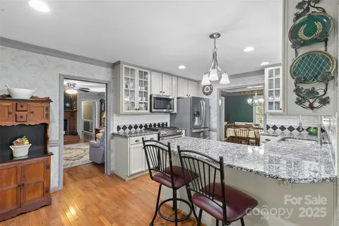 a kitchen with stainless steel appliances granite countertop a kitchen island a stove and a wooden floors