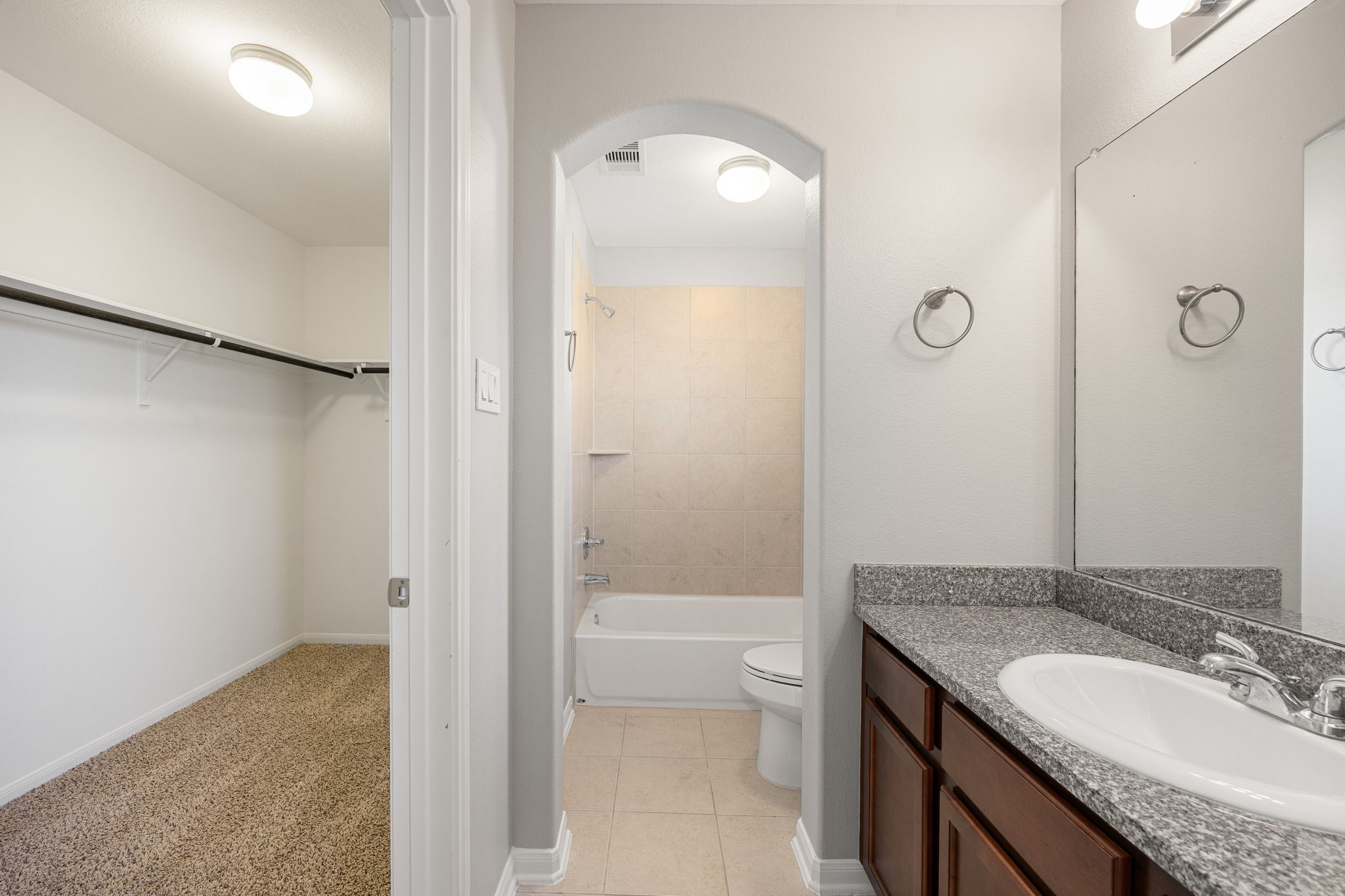 3407 Cardiff Mist Drive Katy, TX 77494 - Photo 20 of 28 This ensuite bathroom boasts tile flooring, a bath/shower combo with a stylish tile surround, stained wood cabinetry, elegant countertops, mirror, and sleek dark fixtures complemented by modern finishes. This space also includes the large walk-in closet!