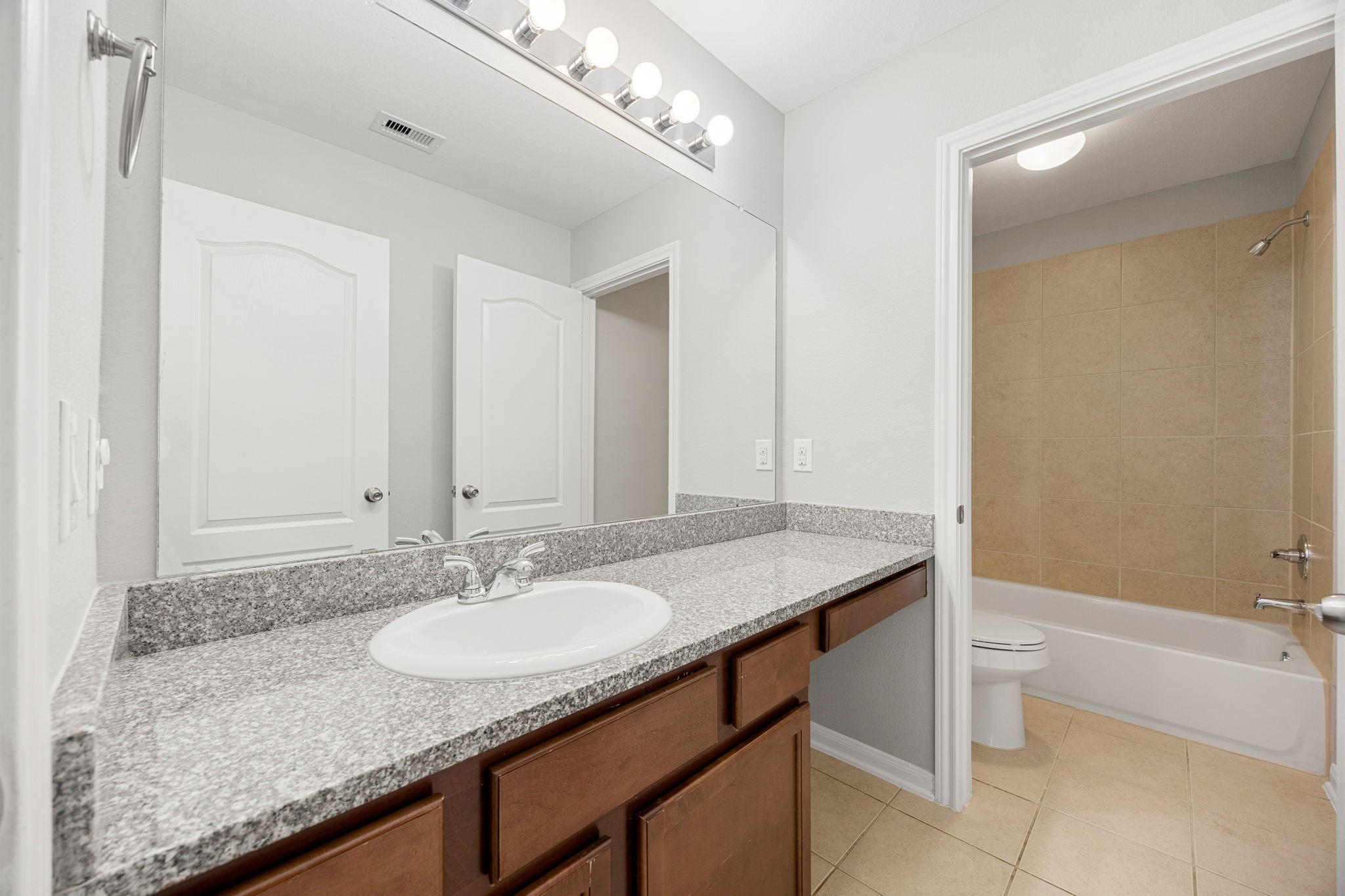 3407 Cardiff Mist Drive Katy, TX 77494 - Photo 22 of 28 Secondary bathroom features elegant countertops and cabinets, custom paint, shower/tub combo with tile surround, large mirror, tile floors, sleek fixtures and modern finishes, plenty of space to accommodate any visiting family or guests.