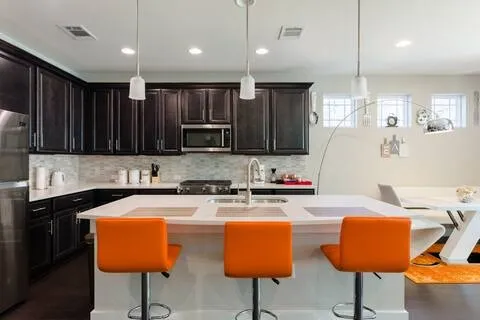 a kitchen with kitchen island granite countertop a stove a sink a counter top space and cabinets