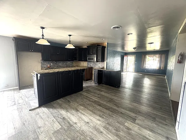 a kitchen with kitchen island granite countertop a sink cabinets and stainless steel appliances