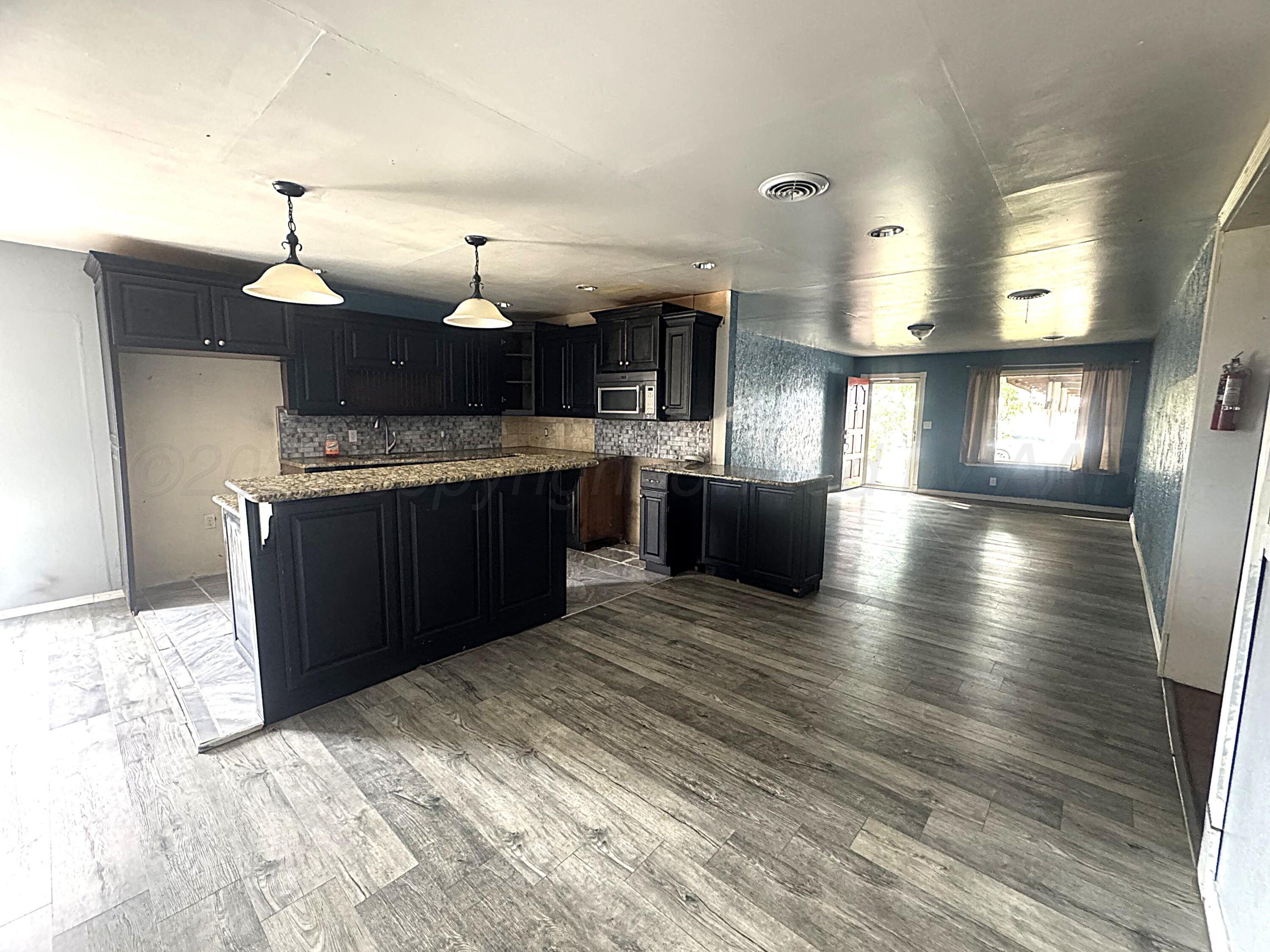 1713 South Drake Street Perryton, TX 79070 - Photo 5 of 13 a kitchen with kitchen island granite countertop a sink cabinets and stainless steel appliances