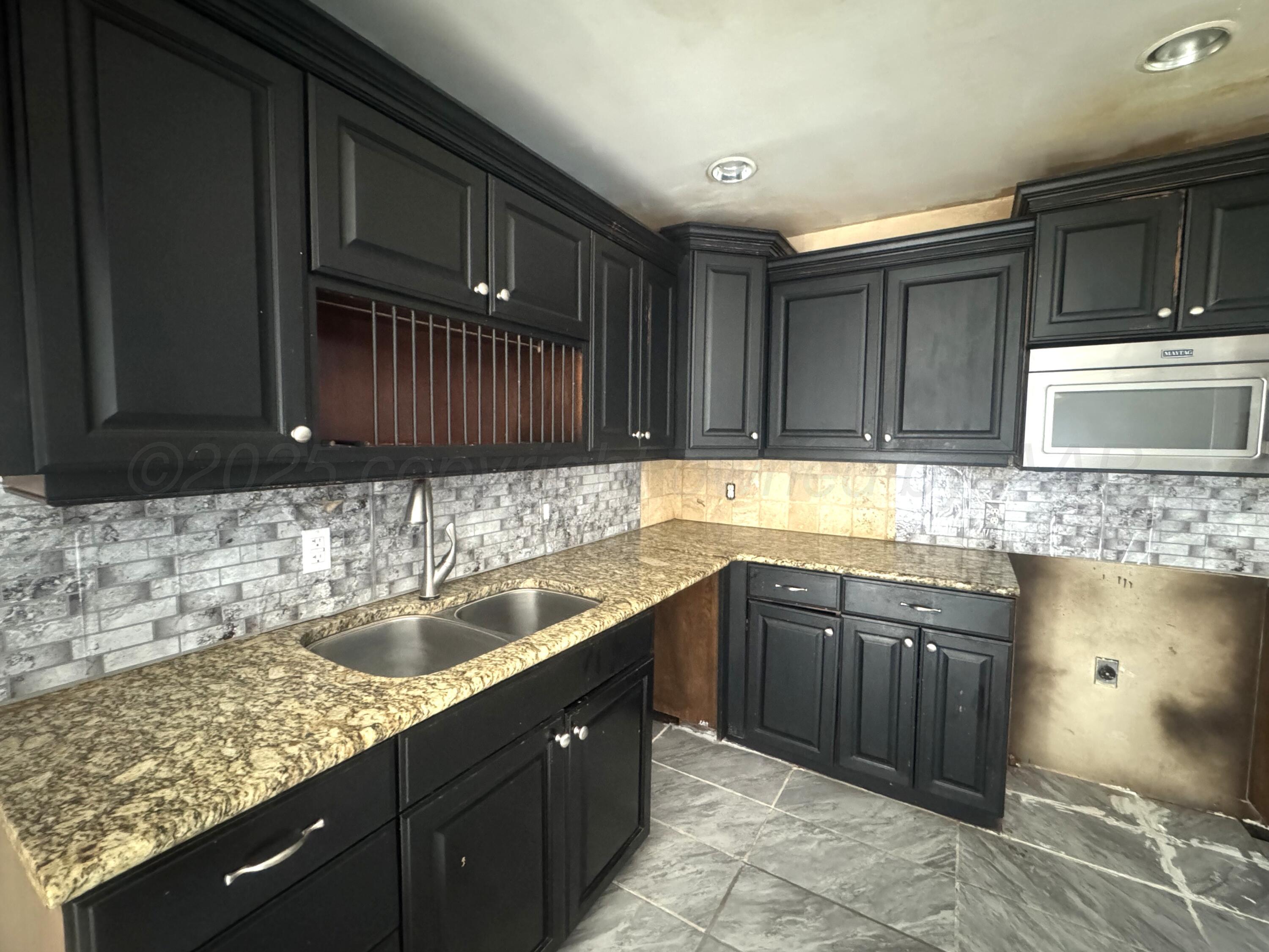 1713 South Drake Street Perryton, TX 79070 - Photo 6 of 13 a kitchen with a sink and wooden cabinets