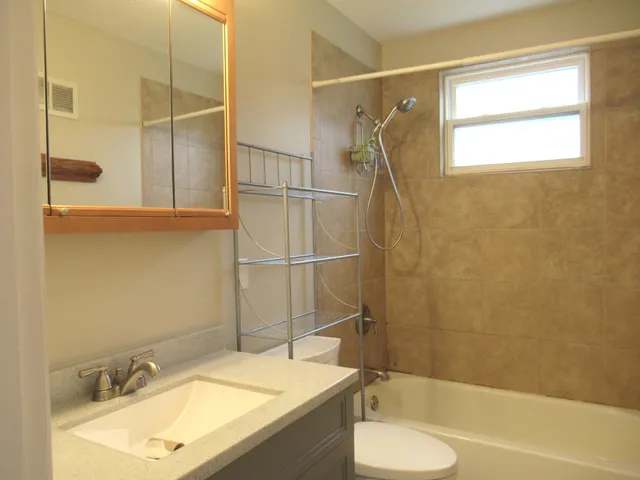 a bathroom with a granite countertop sink toilet and shower