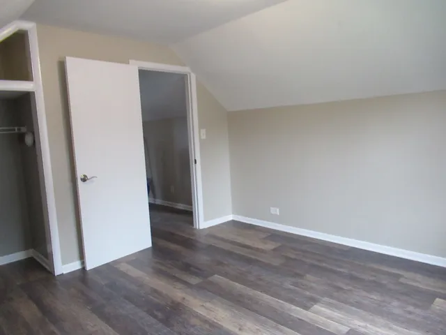 a view of an empty room with wooden floor and closet