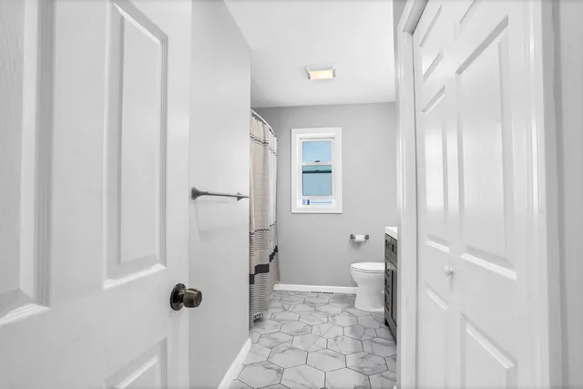 a bathroom with a granite countertop toilet a sink and a mirror