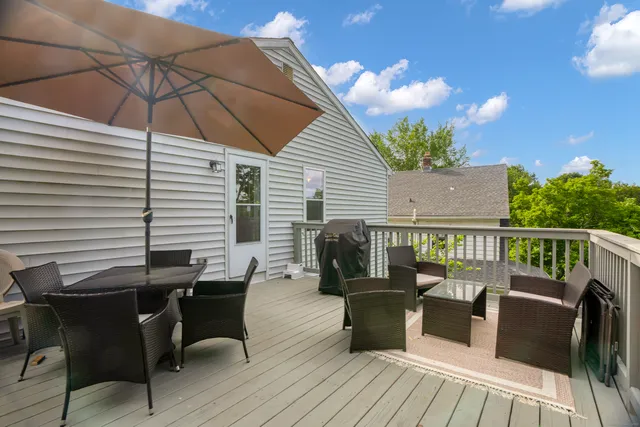 a view of a deck with table and chairs under an umbrella with wooden floor