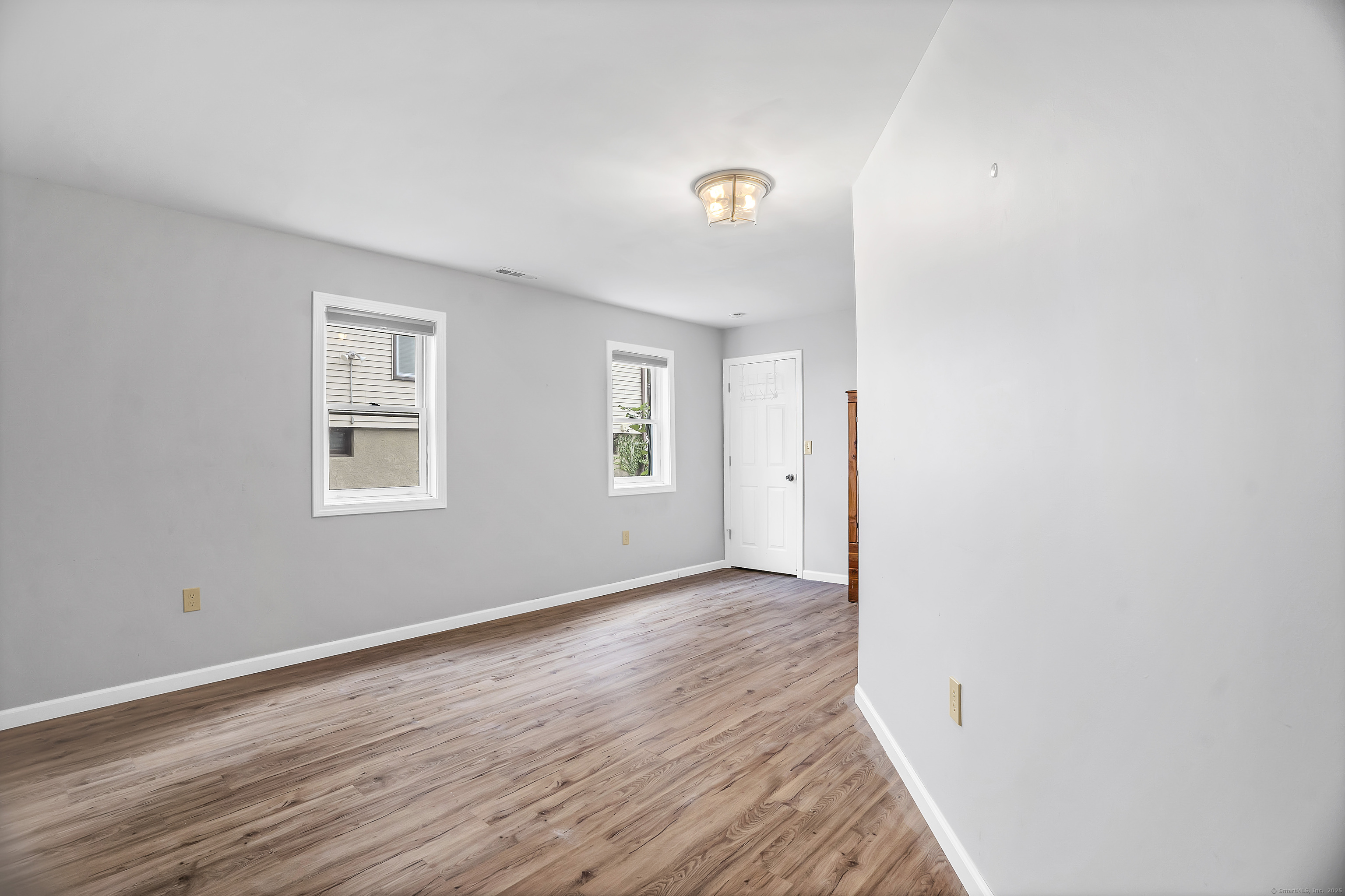 132 Howard Avenue Ansonia, CT 06401 - Photo 5 of 16 an empty room with wooden floor and windows