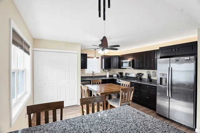 a kitchen with stainless steel appliances granite countertop a stove a refrigerator a sink a dining table and chairs
