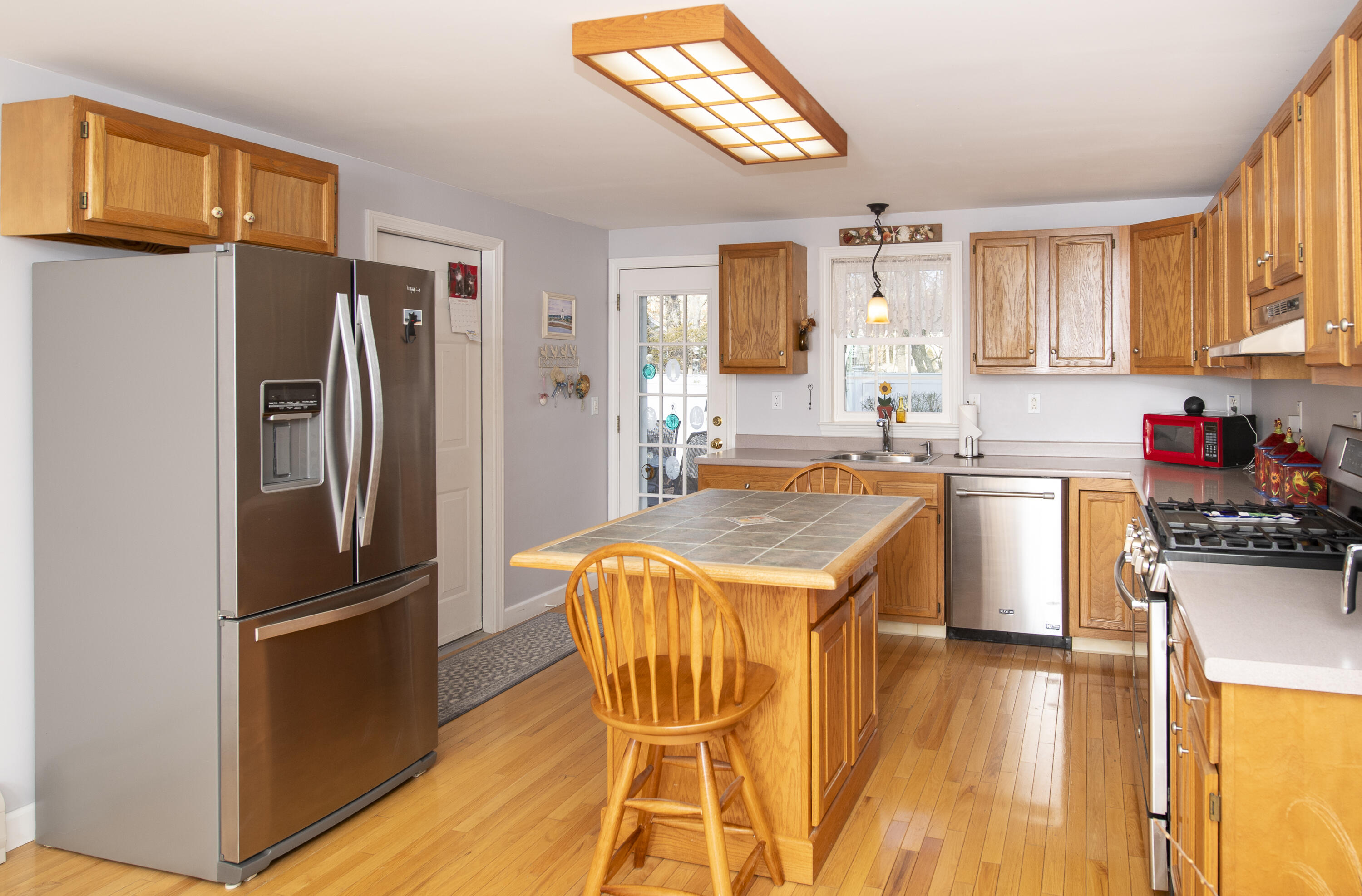 31 Mashpee Neck Road Mashpee, MA 02649 - Photo 15 of 65 a kitchen with stainless steel appliances granite countertop a refrigerator a sink dishwasher a stove with wooden floor and cabinets