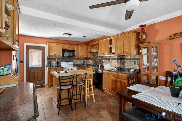 a kitchen with stainless steel appliances kitchen island granite countertop a table chairs and a refrigerator