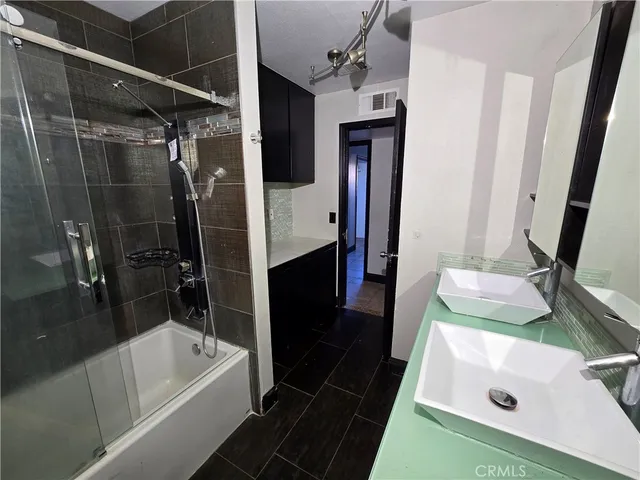 a bathroom with a tub a sink and a large mirror