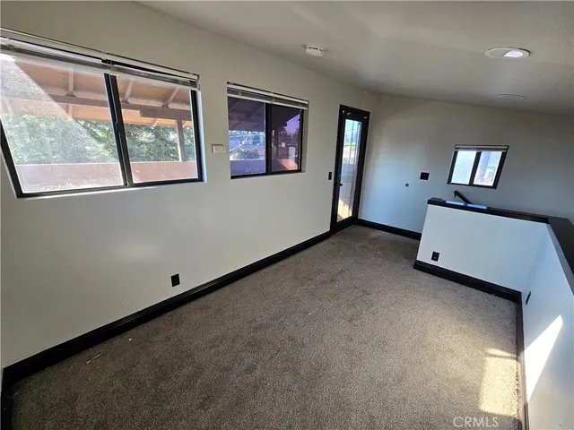 a view of an empty room with wooden floor and windows