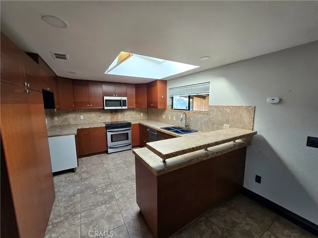 a kitchen with stainless steel appliances granite countertop a stove a sink dishwasher a refrigerator and a microwave oven