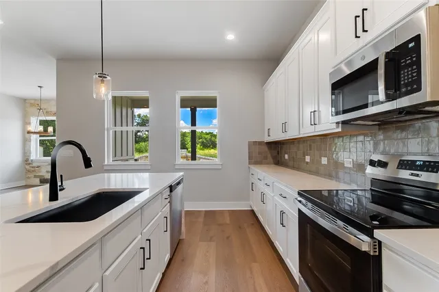 a kitchen with stainless steel appliances a sink a stove and microwave