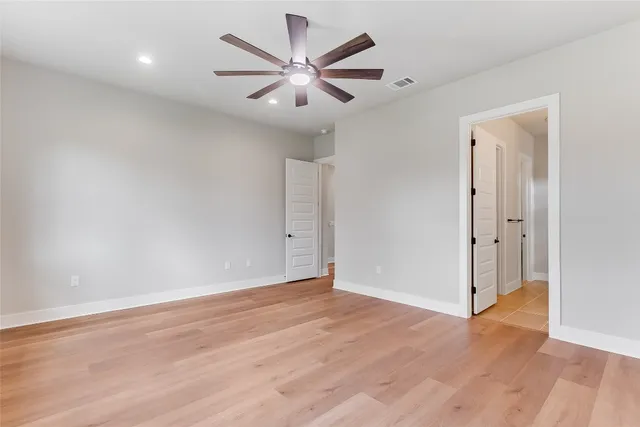 an empty room with wooden floor and a ceiling fan