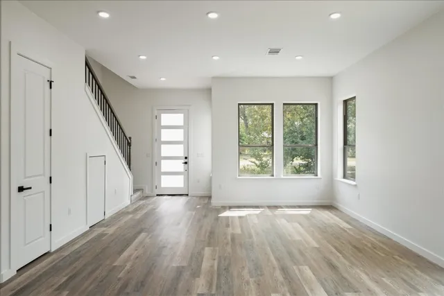 a view of empty room with wooden floor and fan
