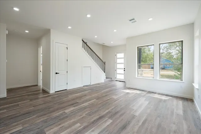 an empty room with wooden floor and windows
