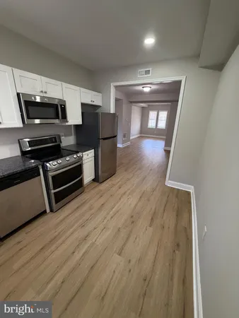 a view of kitchen with wooden floor cabinets and stainless steel appliances