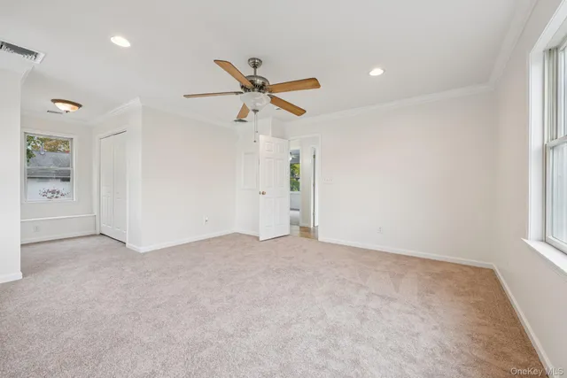an empty room with windows and ceiling fan