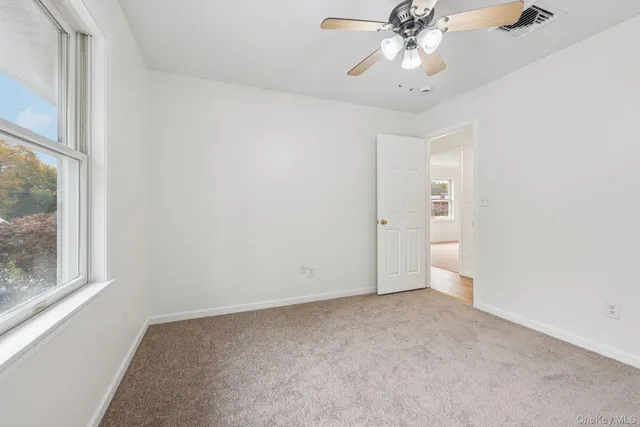 an empty room with a window and a fan