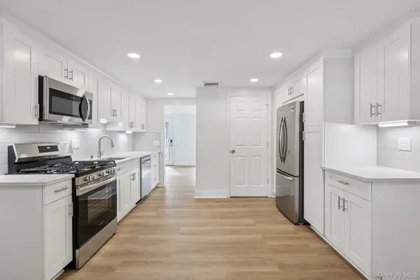 a kitchen with stainless steel appliances granite countertop a refrigerator a stove a sink and a microwave