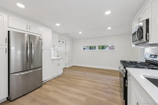 a kitchen with stainless steel appliances a table chairs and a refrigerator