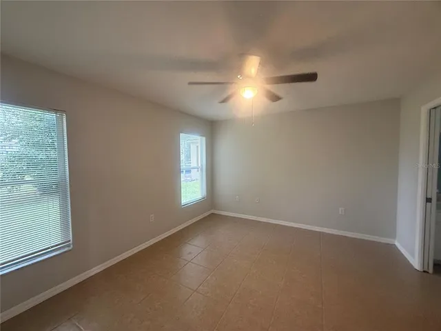 an empty room with windows and fan