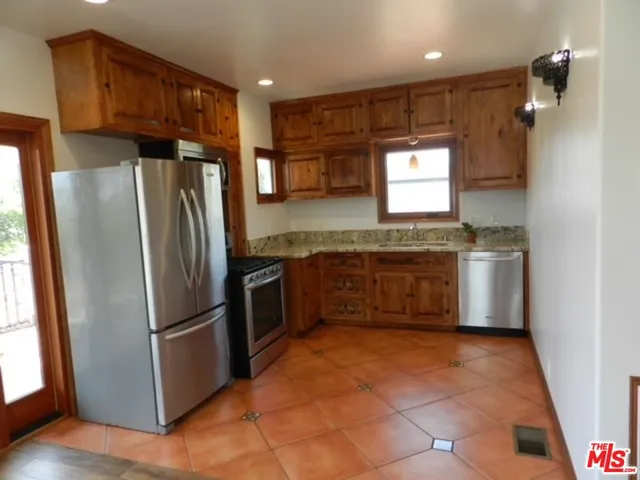 a kitchen with stainless steel appliances granite countertop a refrigerator a sink a stove and island