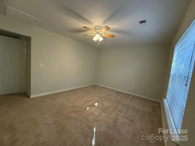 an empty room with a chandelier fan and windows