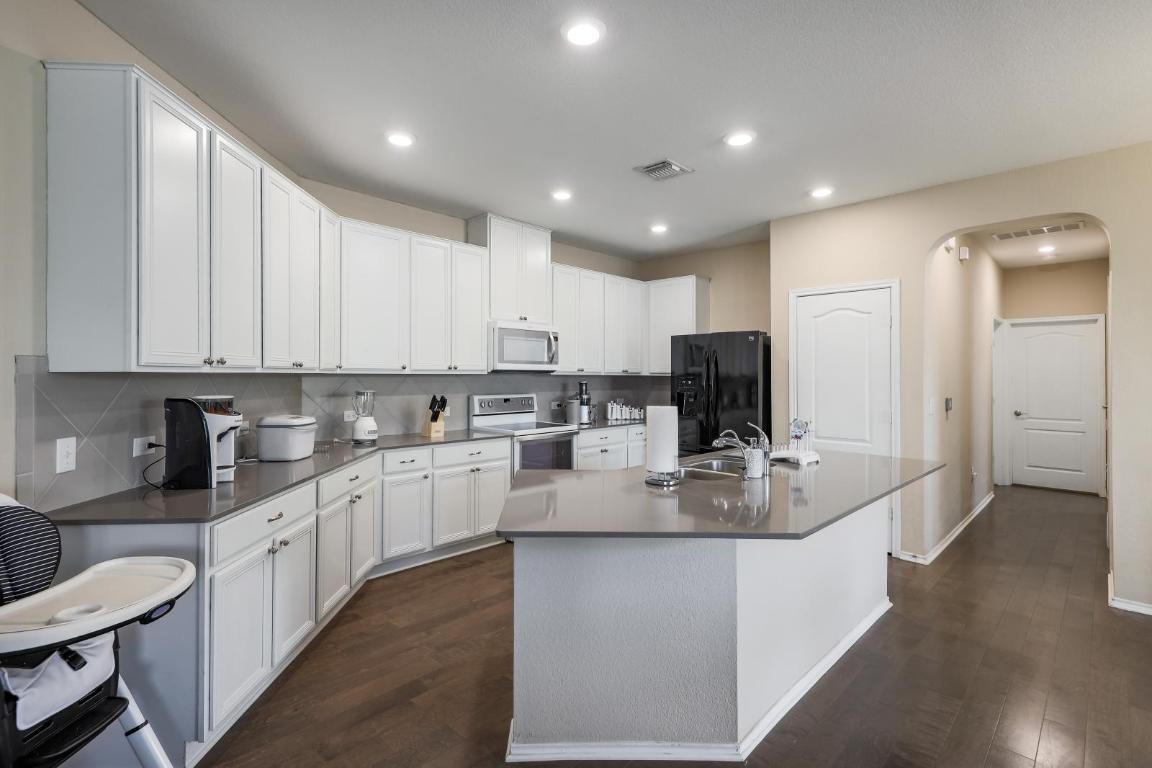 6300 Garden Rose Path Austin, TX 78754 - Photo 11 of 25 a kitchen with stainless steel appliances granite countertop a stove top oven a sink a refrigerator and white cabinets