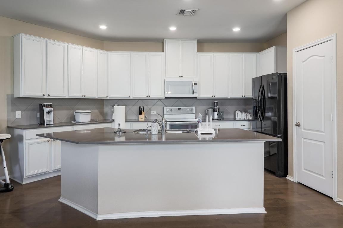 6300 Garden Rose Path Austin, TX 78754 - Photo 12 of 25 a kitchen with stainless steel appliances granite countertop a refrigerator a sink a stove a microwave and white cabinets