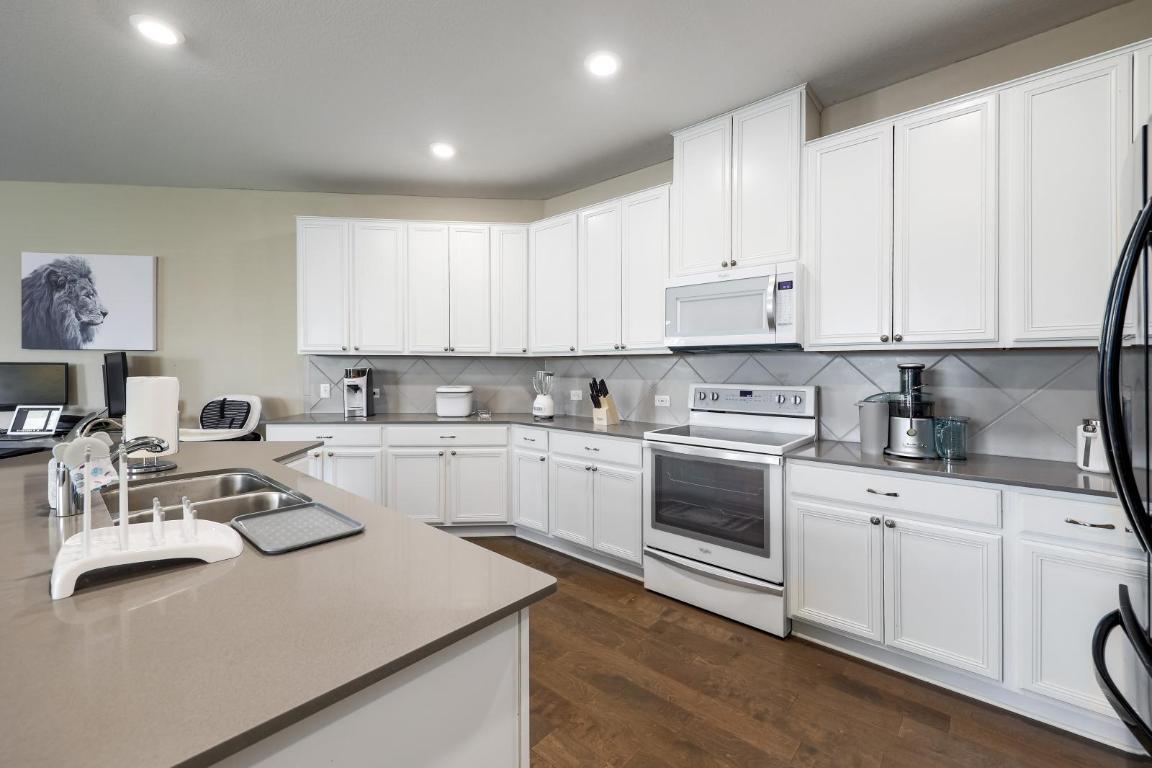 6300 Garden Rose Path Austin, TX 78754 - Photo 13 of 25 a kitchen with granite countertop white cabinets and white appliances
