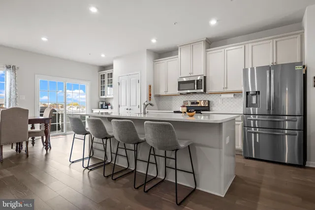 a kitchen with kitchen island granite countertop lots of white cabinets appliances and furniture