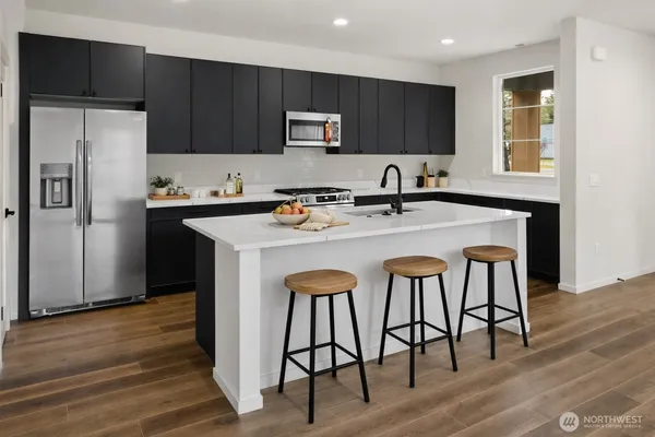 a kitchen with stainless steel appliances granite countertop a stove a refrigerator a sink a stove and island with wooden floor