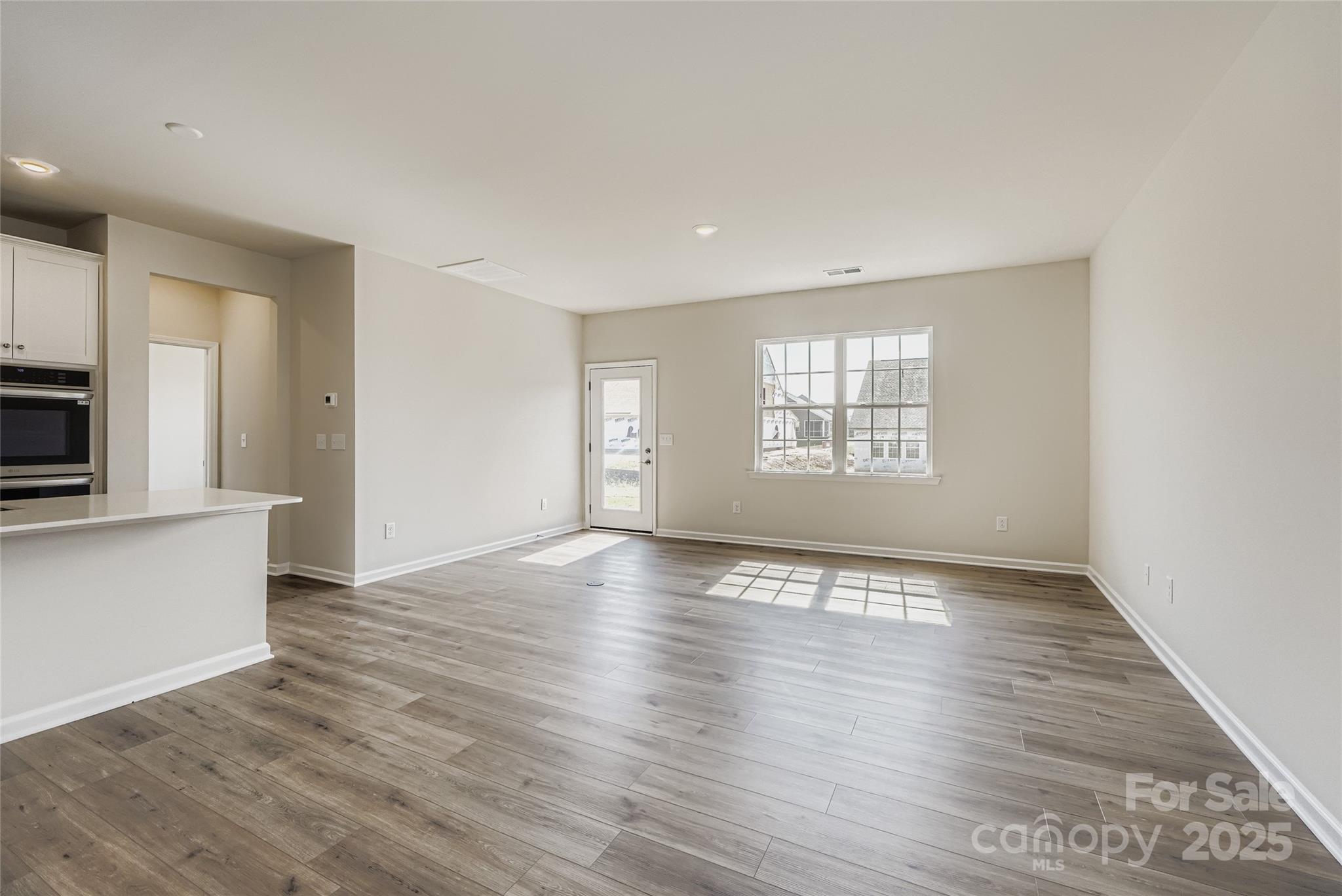 8487 Norman Frst Road Lancaster, SC 29720 - Photo 3 of 16 an empty room with wooden floor and windows