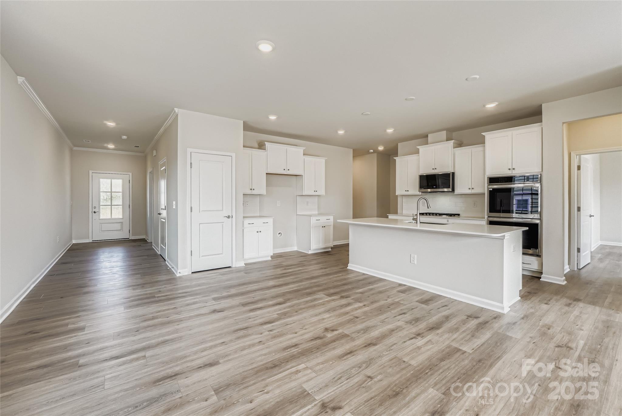 8487 Norman Frst Road Lancaster, SC 29720 - Photo 5 of 16 a large kitchen with kitchen island a stove a refrigerator white cabinets and wooden floor