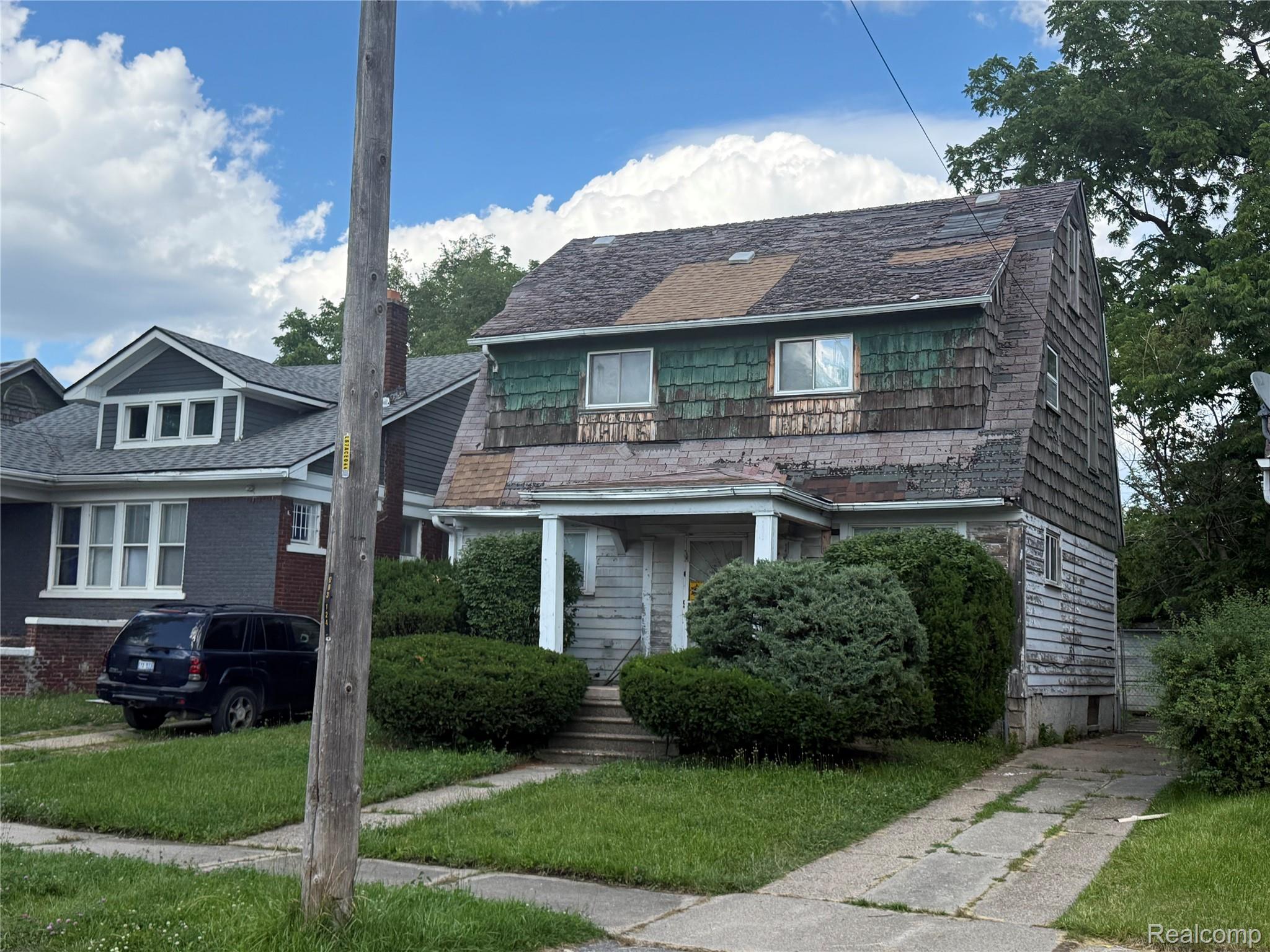 13276 Strathmoor Street Detroit, MI 48227 - Photo 2 of 13 Front facade with a covered porch, established shrubbery, and a concrete driveway