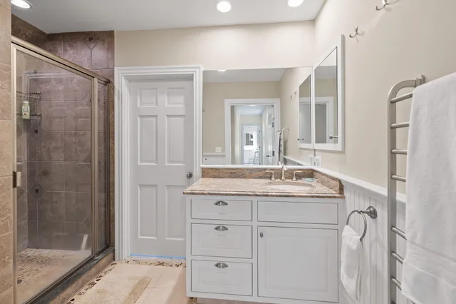 a bathroom with a granite countertop sink a mirror a glass door and shower
