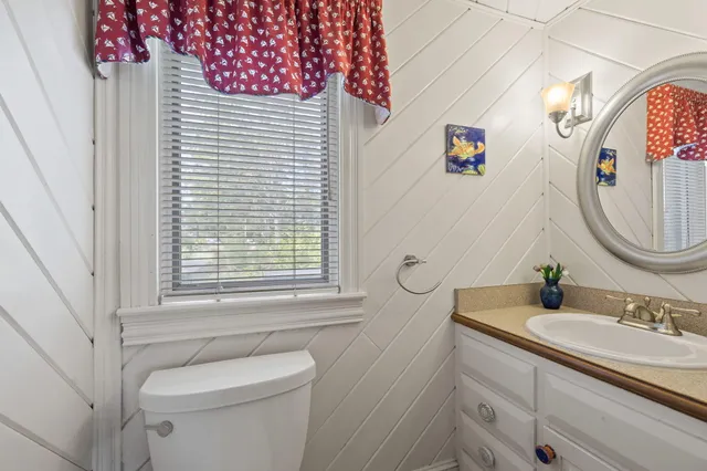a bathroom with a toilet sink vanity granite and mirror