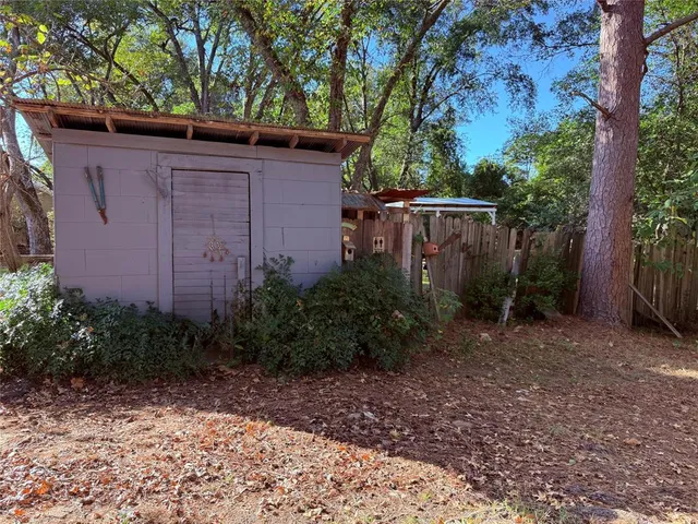 a view of a backyard with plants and large trees